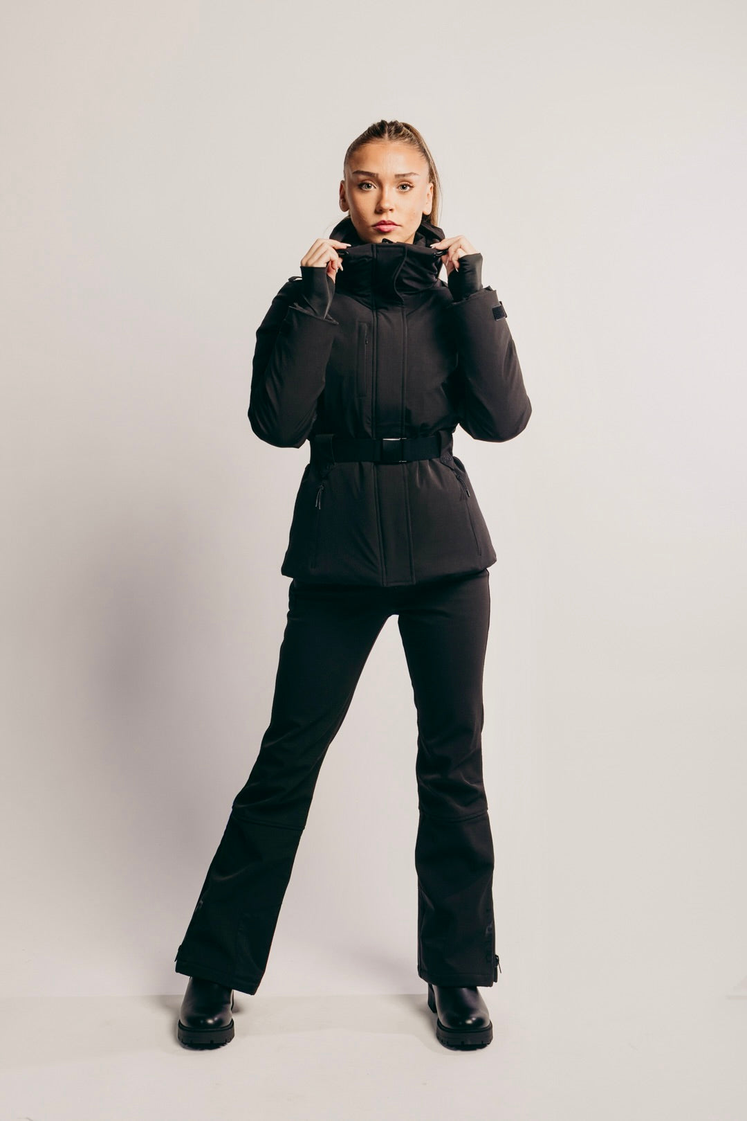 Person wearing a black winter outfit on a light gray background