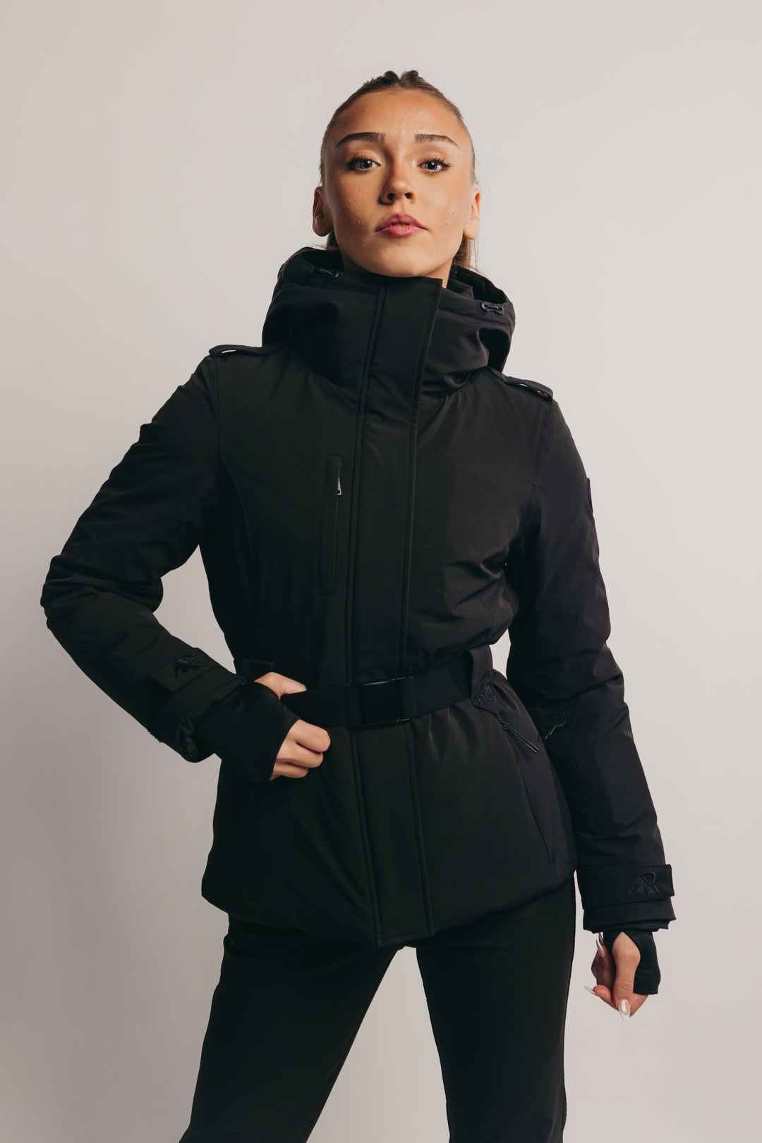 Person wearing a black ski jacket and pants on a plain background