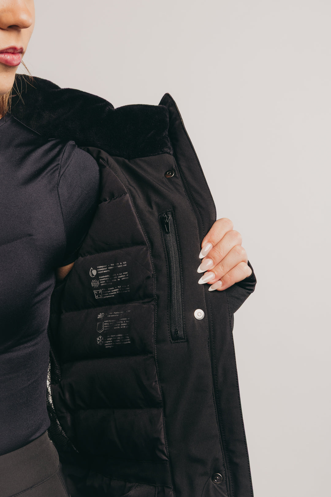 Black ski coat with multiple pockets on a plain background