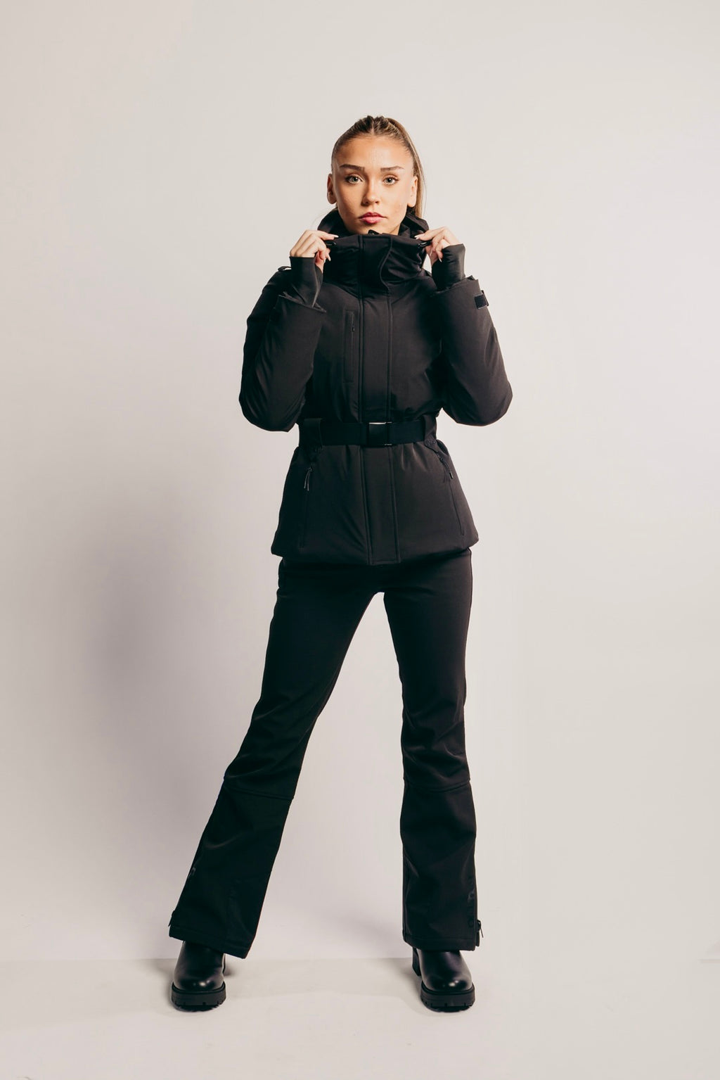 Person wearing a black winter outfit on a light gray background