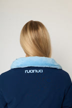 Back view of a person wearing a navy blue puffer jacket with a light blue fleece collar. The brand name 'ruanua' is printed in white on the upper back.